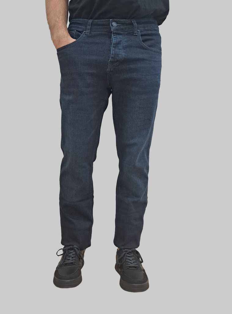 Person wearing dark blue jeans on a gray background